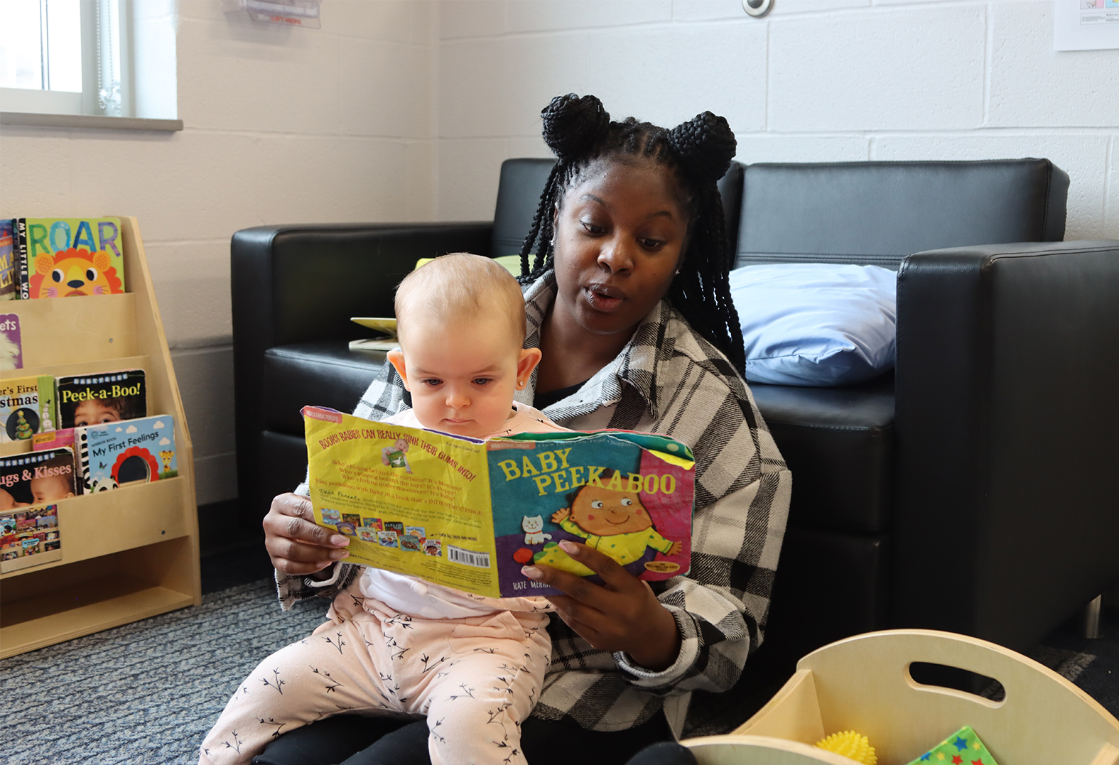 A PLASP educator reads a storybook to an infant in program